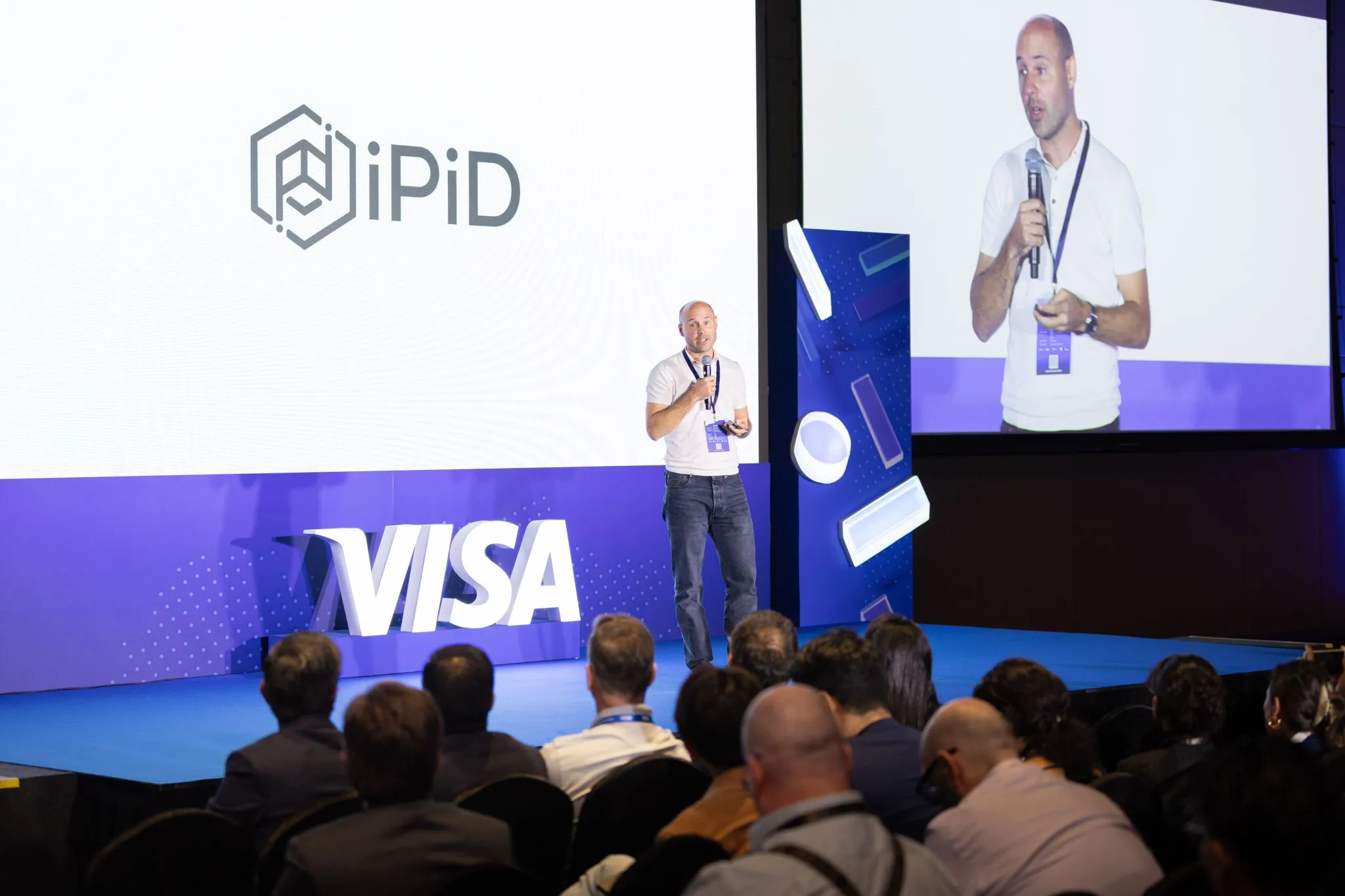 iPiD CEO presenting at a Visa conference with the iPiD brand displayed on stage.